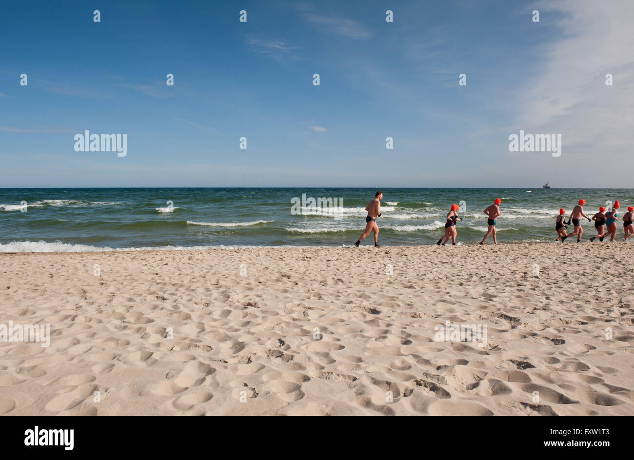 Winter swimmers warm up running along the beach in Wladyslawowo seashore, Poland, Europe, people during active sport in sea Stock Photo