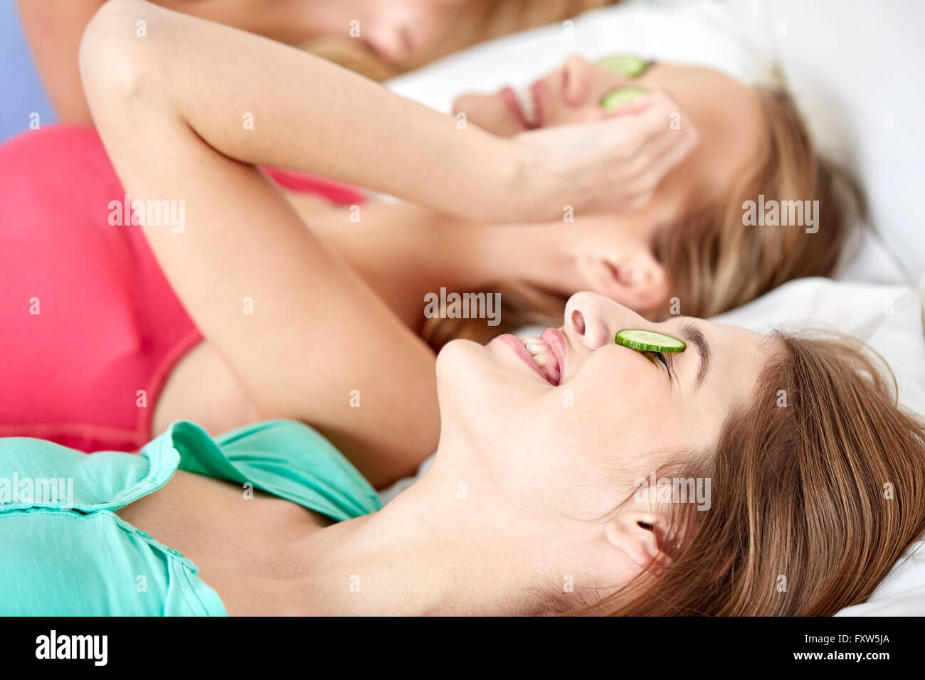 happy young women with cucumber mask lying in bed Stock Photo