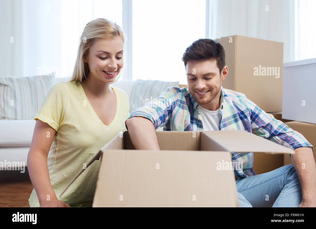 smiling couple with big boxes moving to new home Stock Photo - Alamy