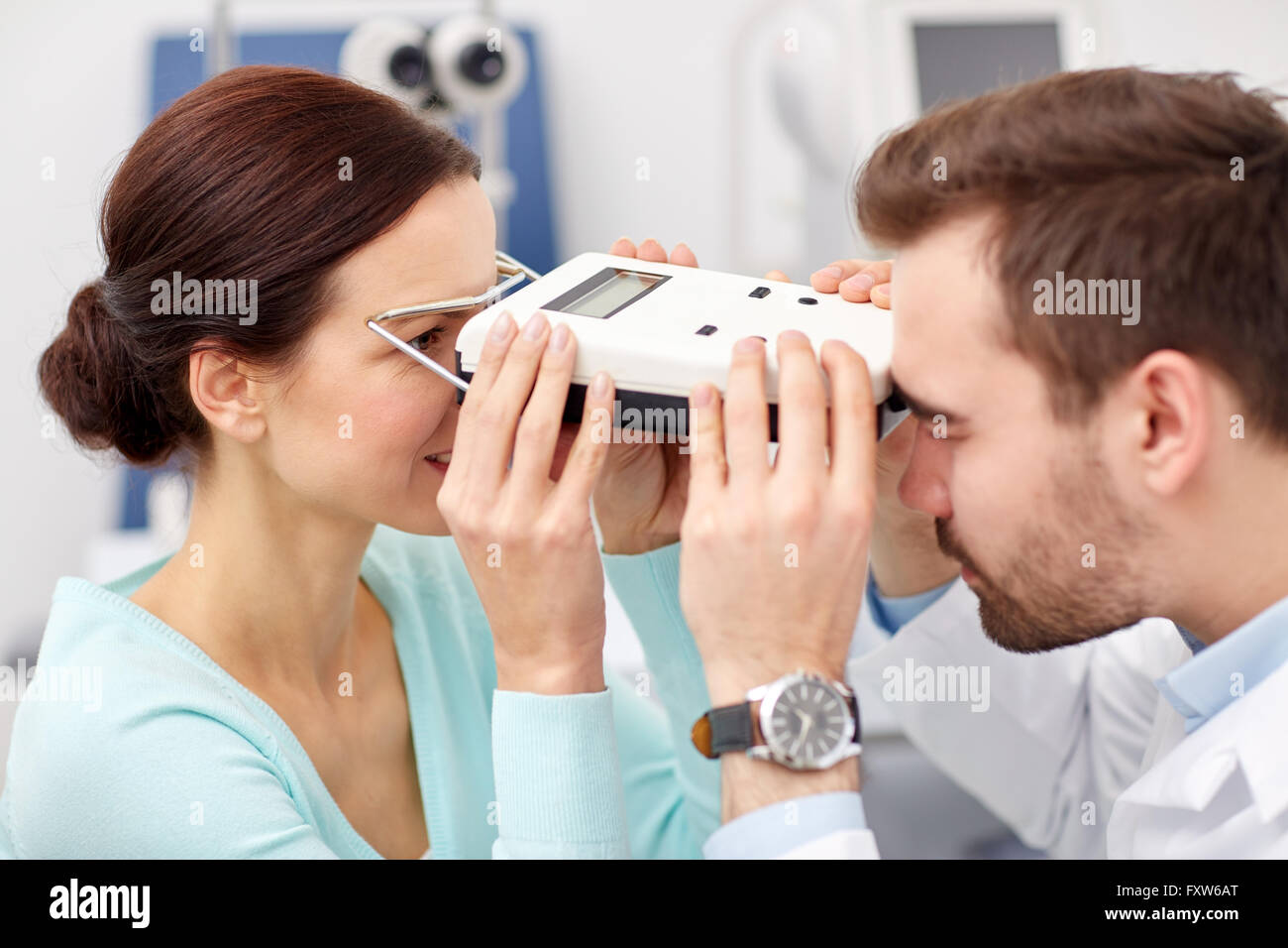 optician with pupilometer and patient at eye clinic Stock Photo