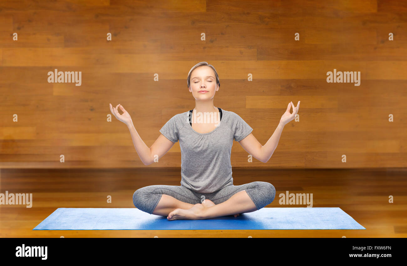 woman making yoga meditation in lotus pose on mat Stock Photo - Alamy