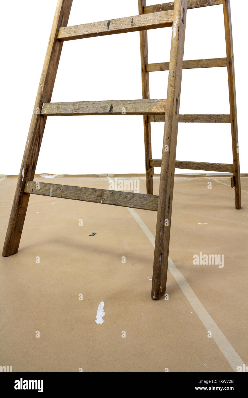 Bottom of a wood ladder on a paperboard covered floor Stock Photo