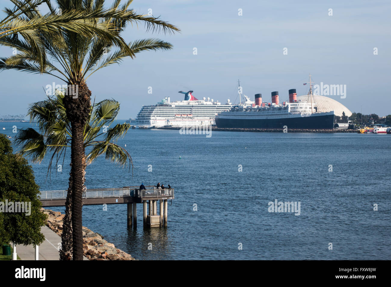The Queen Mary berthed at Longbeach California with carnival cruiseliner in the background, palm tree in the foreground Stock Photo