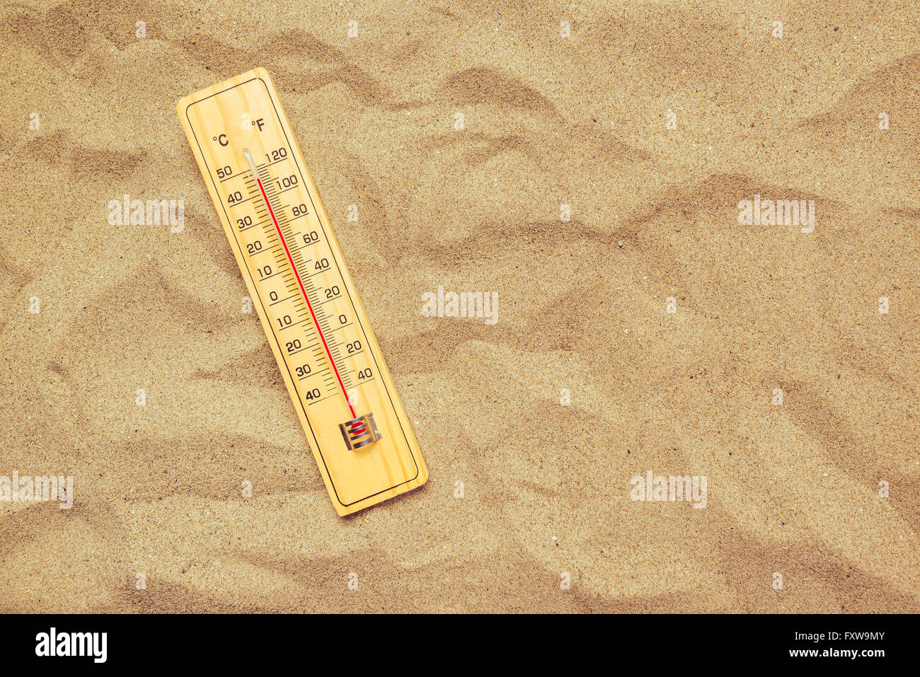 Record high temperatures, thermometer with celsius and farenheit scale on warm desert sand. Stock Photo