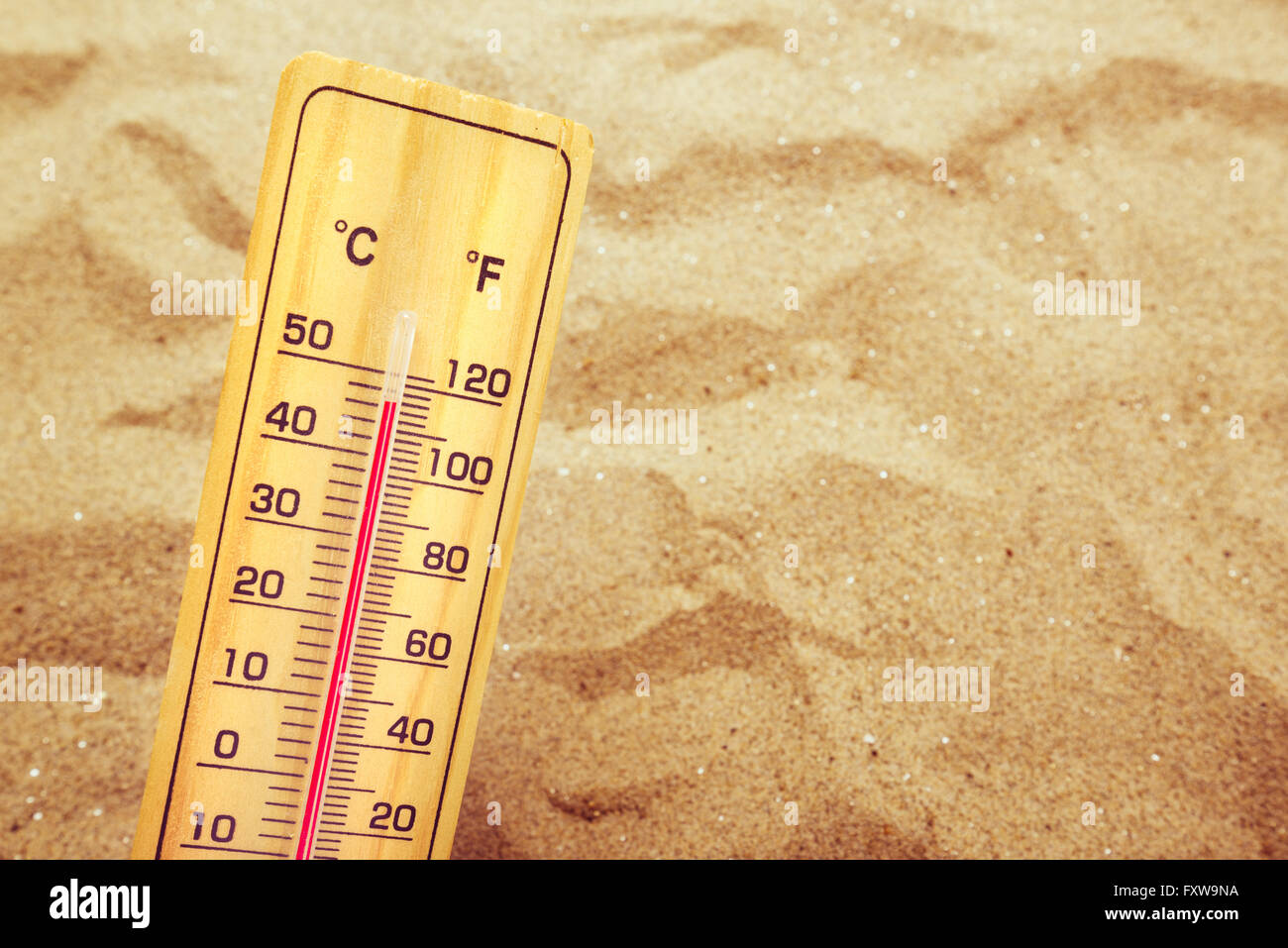 Extremely high temperatures, thermometer with celsius and farenheit scale on warm desert sand. Stock Photo