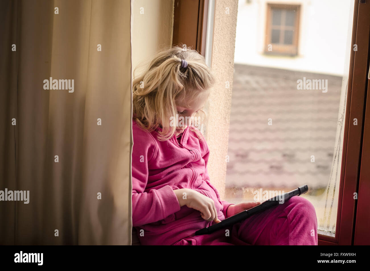 beautiful blond kid playing with tablet device Stock Photo