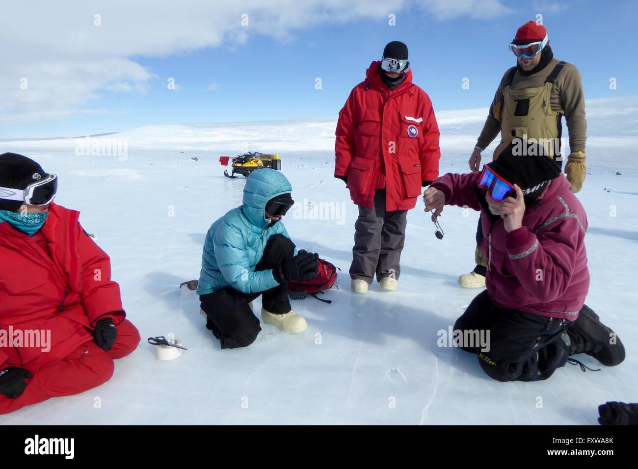 Researchers examine a meteorite found on the blue ice field in the Miller Range December 18, 2015 in Antarctica. Scientists collected 570 meteorite samples during a two-month expedition as part of the Antarctic Search for Meteorites program. Stock Photo
