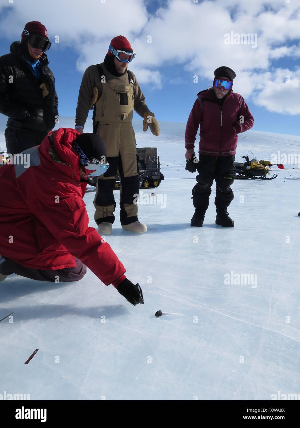 Researchers examine a meteorite found on the blue ice field in the Miller Range December 19, 2015 in Antarctica. Scientists collected 570 meteorite samples during a two-month expedition as part of the Antarctic Search for Meteorites program. Stock Photo