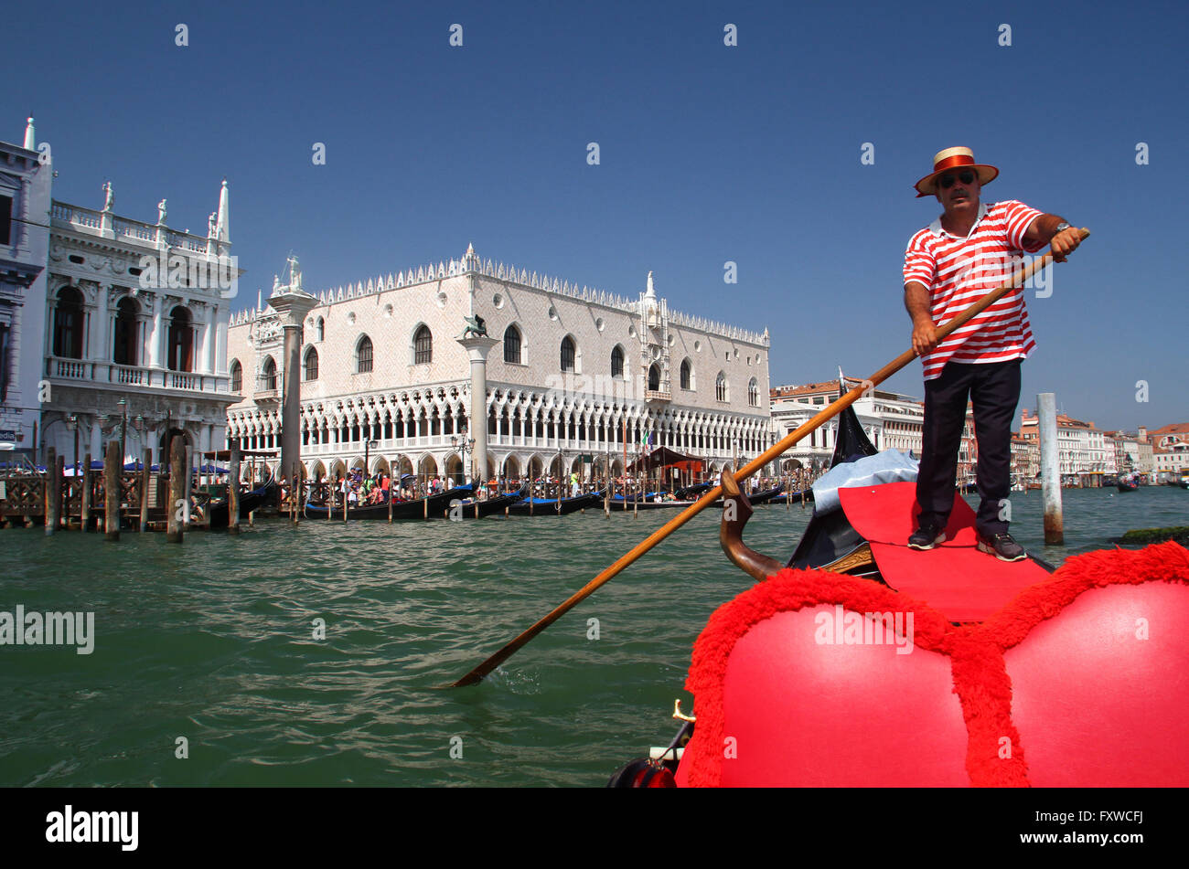 GONDOLIER IN RED HOOPS GRAND CANAL VENICE ITALY 04 August 2014 Stock Photo