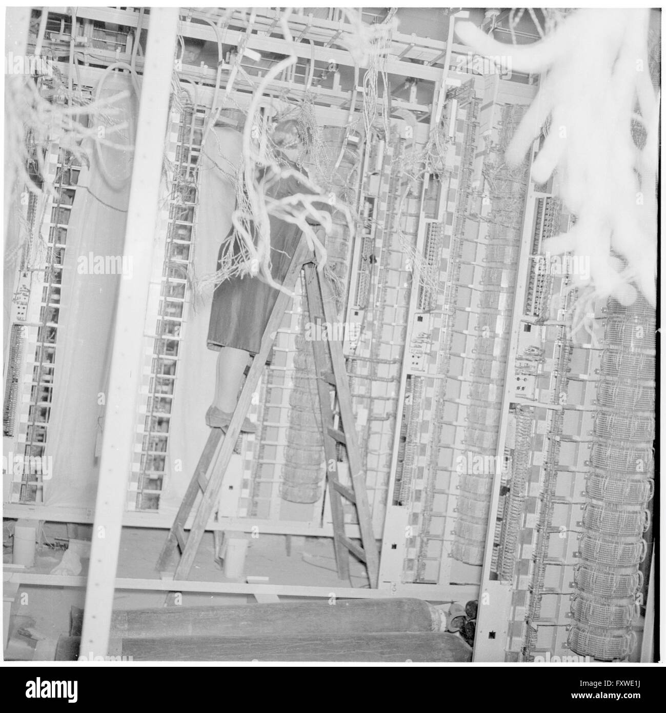 Telefonistin auf einer Leiter, technische Anlage ... Stock Photo