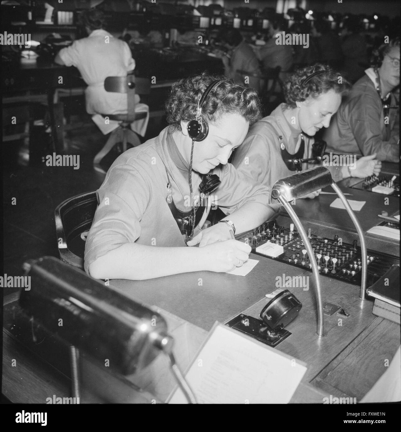 Telefonistinnen an Tischen, arbeiten. Telefon ... Stock Photo