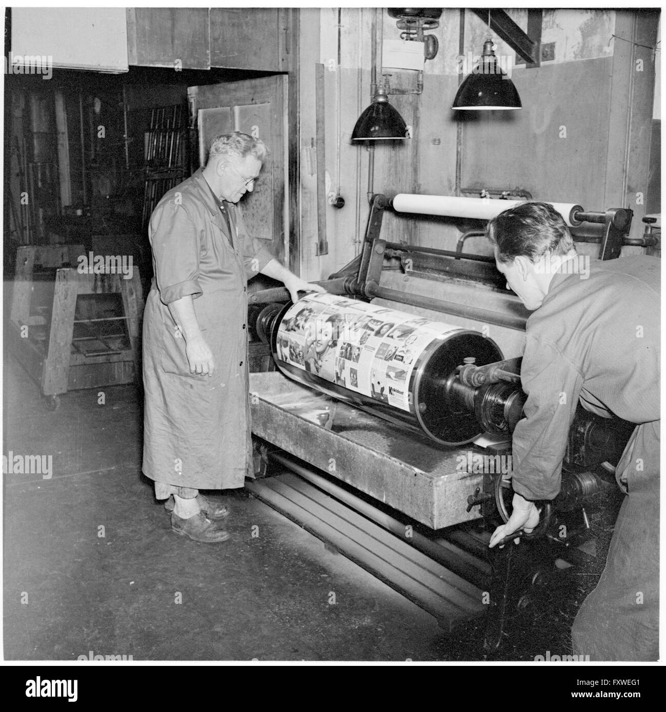 Zwei Arbeiter an einer Drucker-Walze. Druckerei ... Stock Photo