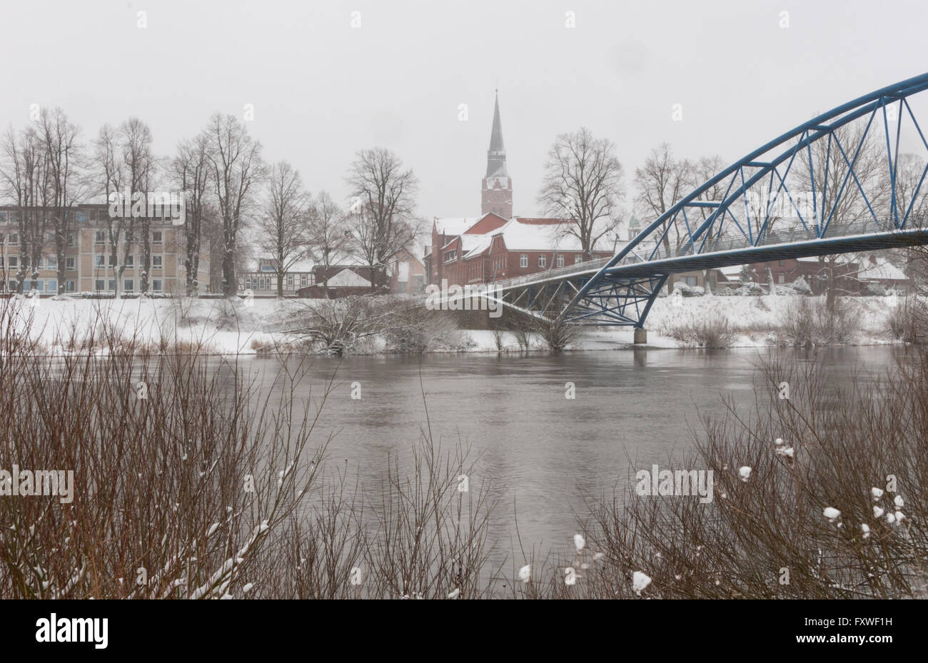 Cityscape of Nienburg in winter with church tower, houses, rampart, Weser and pedestrian bridge seen from the opposite bank of t Stock Photo