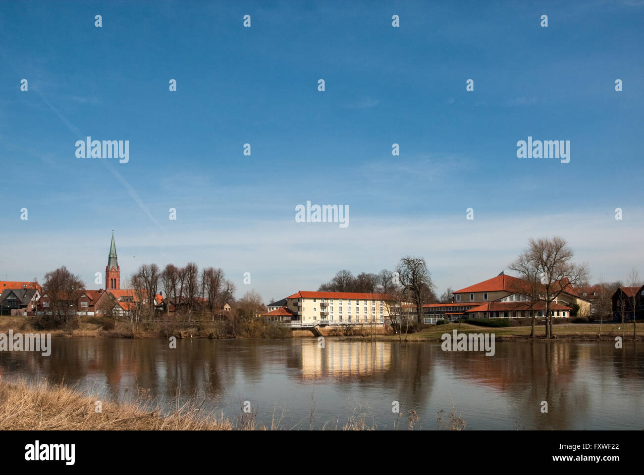 Cityscape of Nienburg with church tower, houses, rampart and Weser seen from the opposite bank of the river Weser Stock Photo