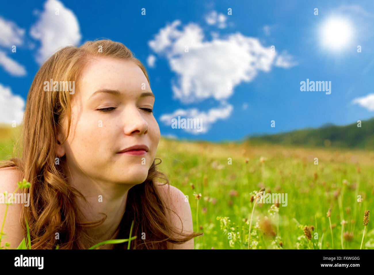 Young woman with closed eyes lying on a meadow Stock Photo - Alamy