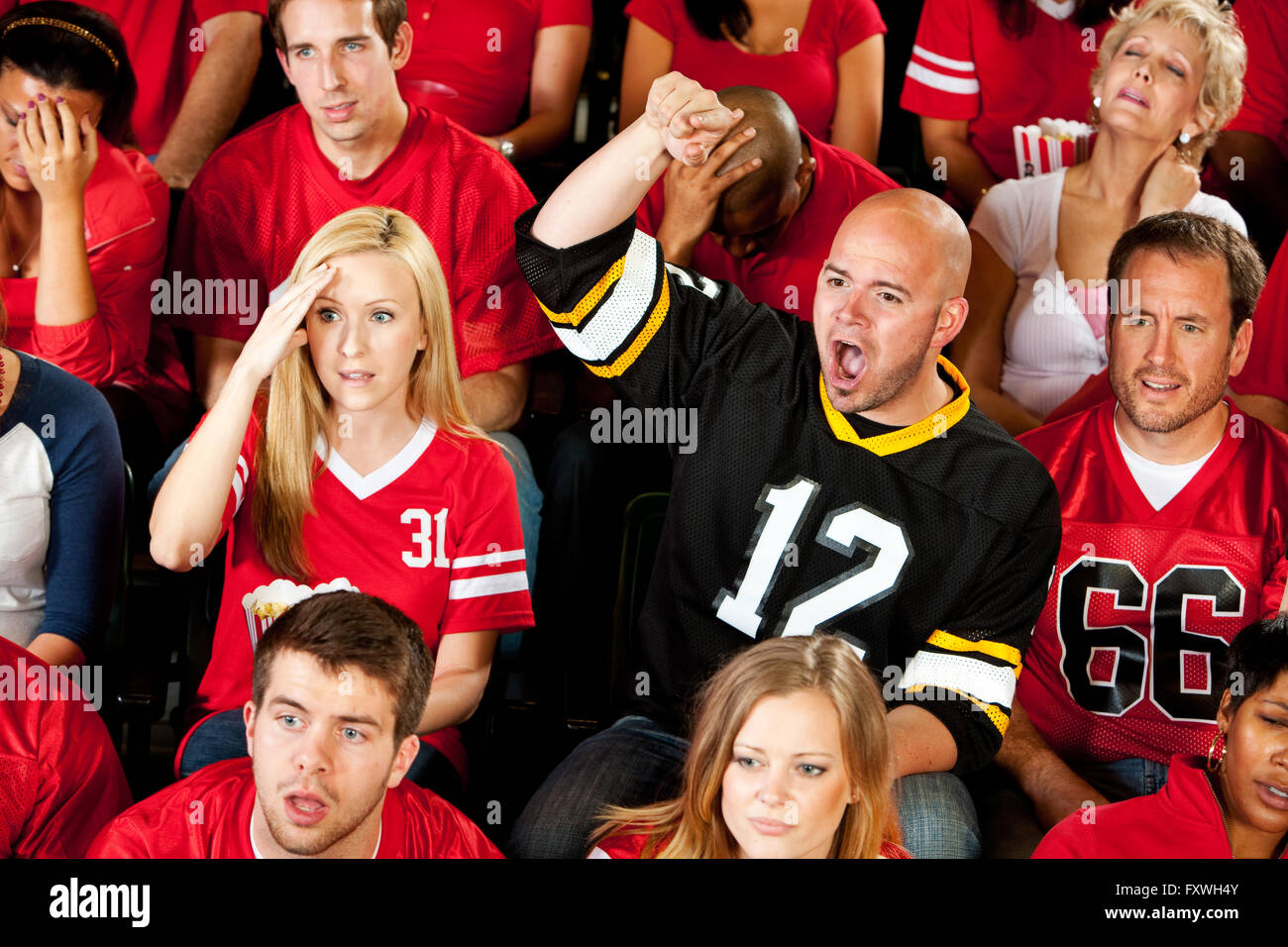 Multi-ethnic crowd of American football fans in a stadium, cheering, eating and having fun. Stock Photo