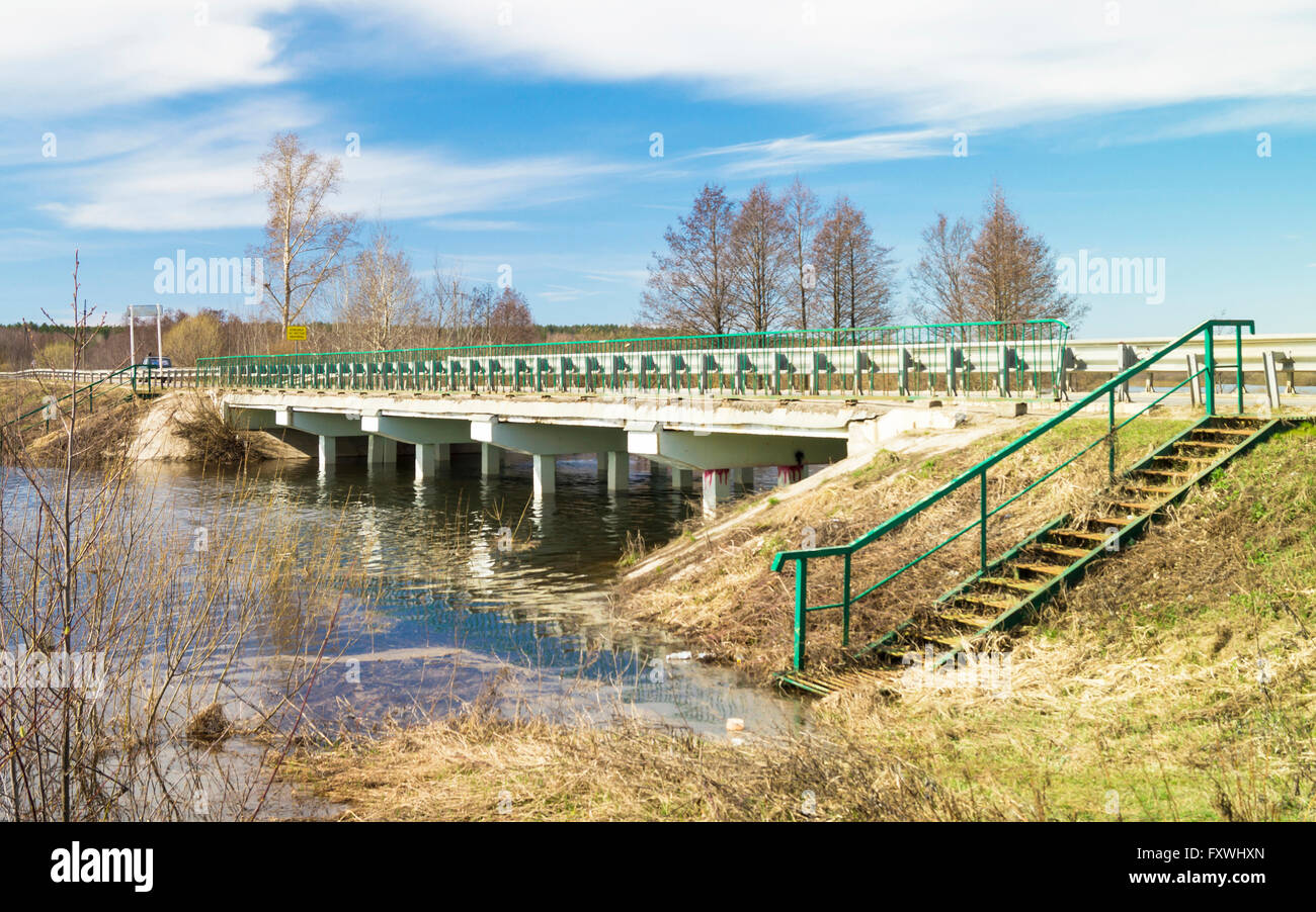 Spring landscape with concrete bridge through river on background blue sky Stock Photo