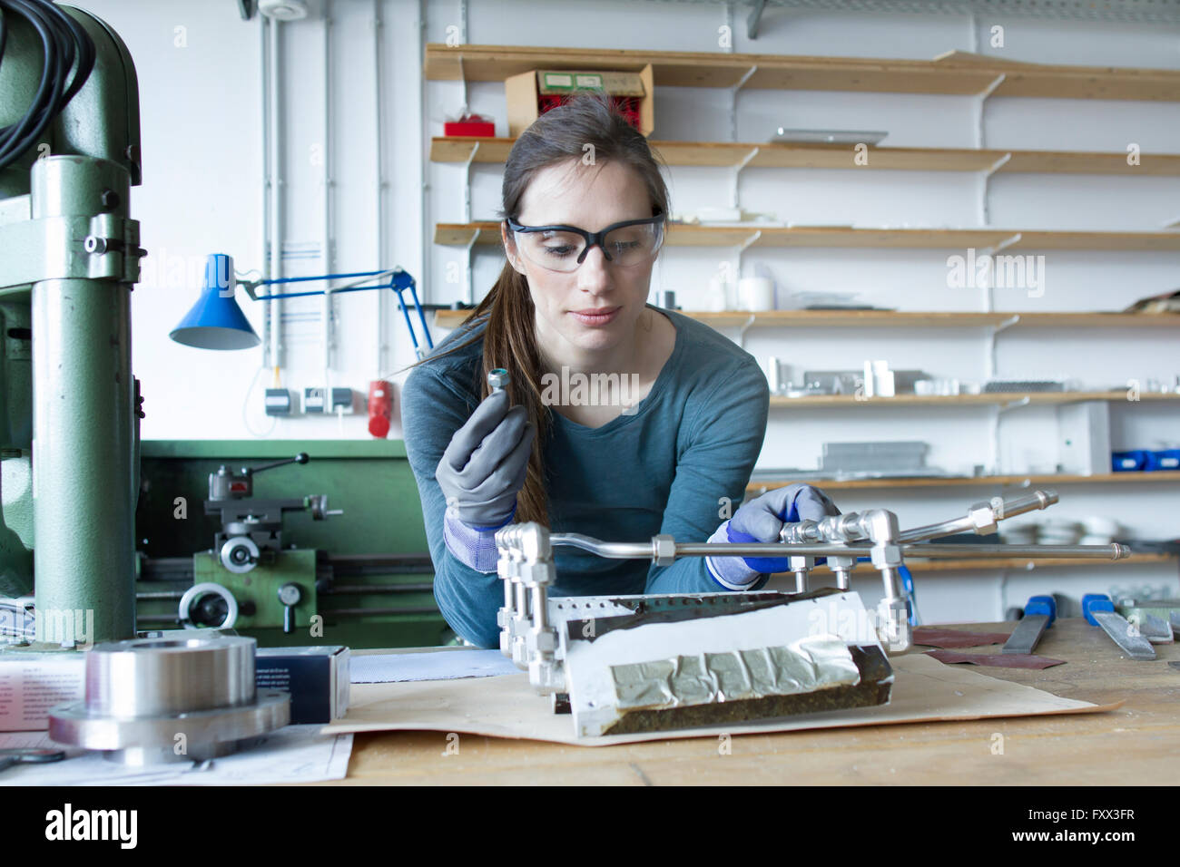 Woman wearing latex gloves and safety goggles building model Stock