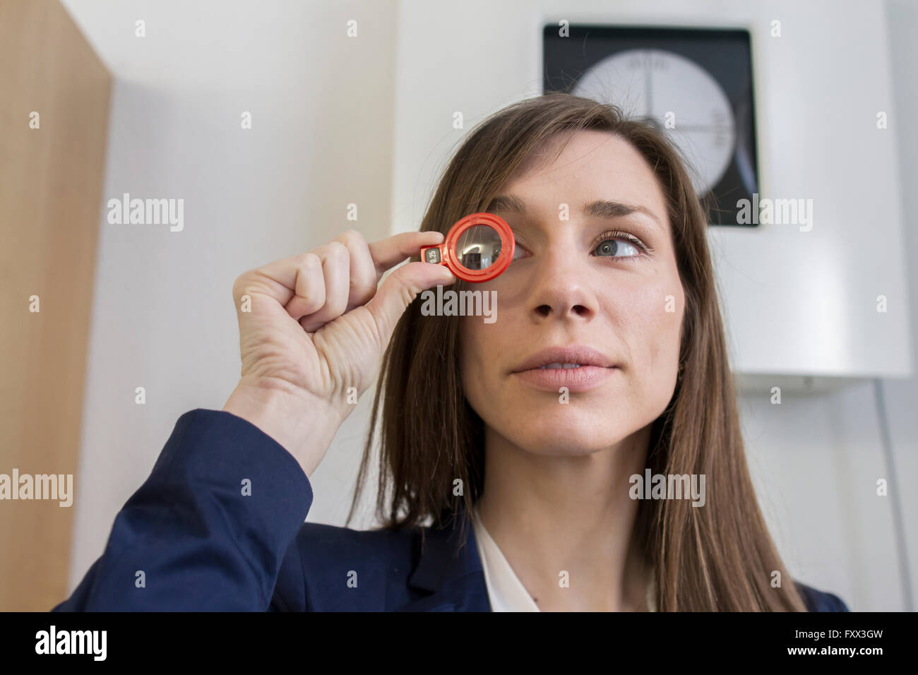 Woman in opticians office looking through optical tool Stock Photo Alamy