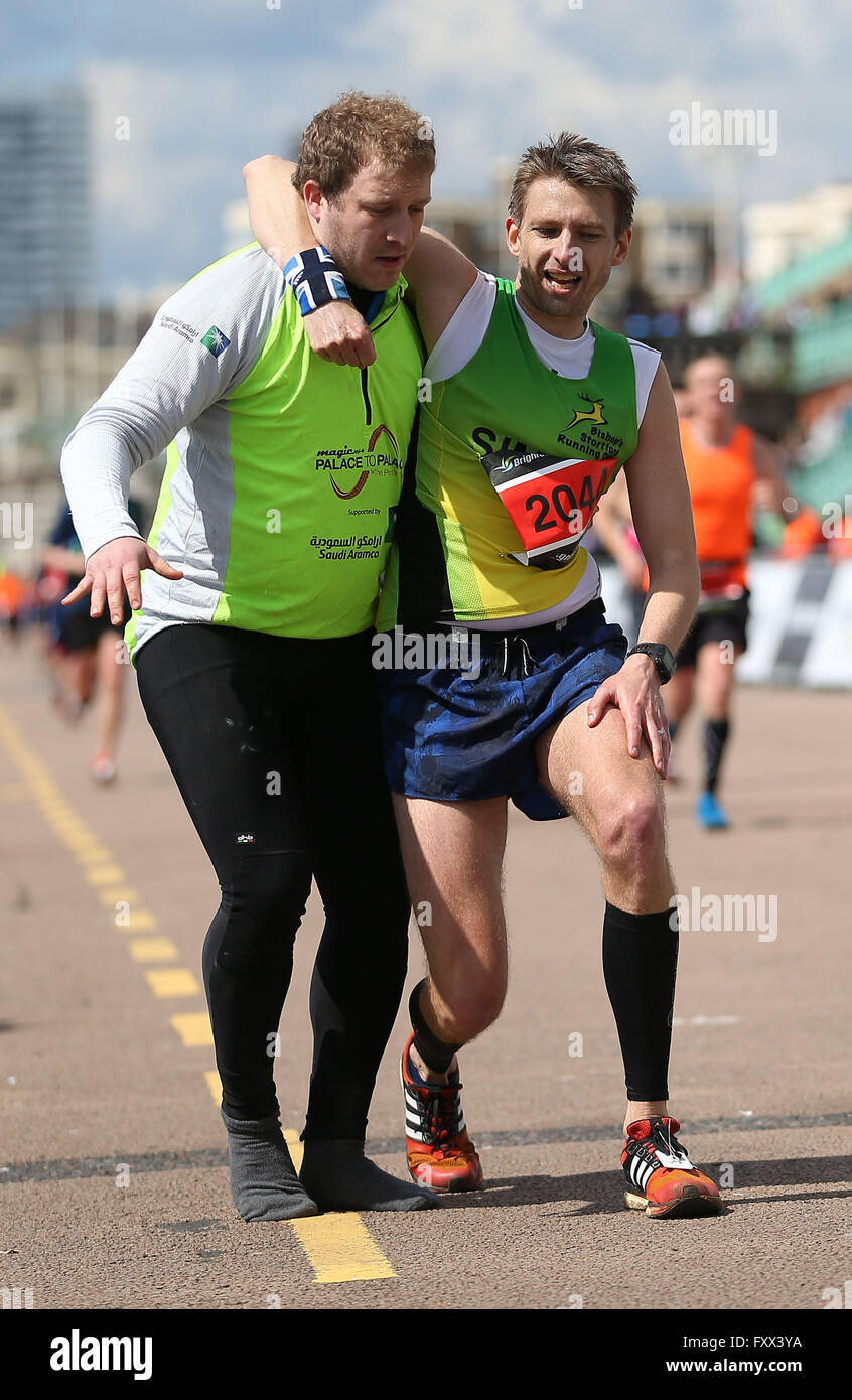 A Official helps an exhausted runner reach the finish line of the 2016 Brighton Marathon Stock