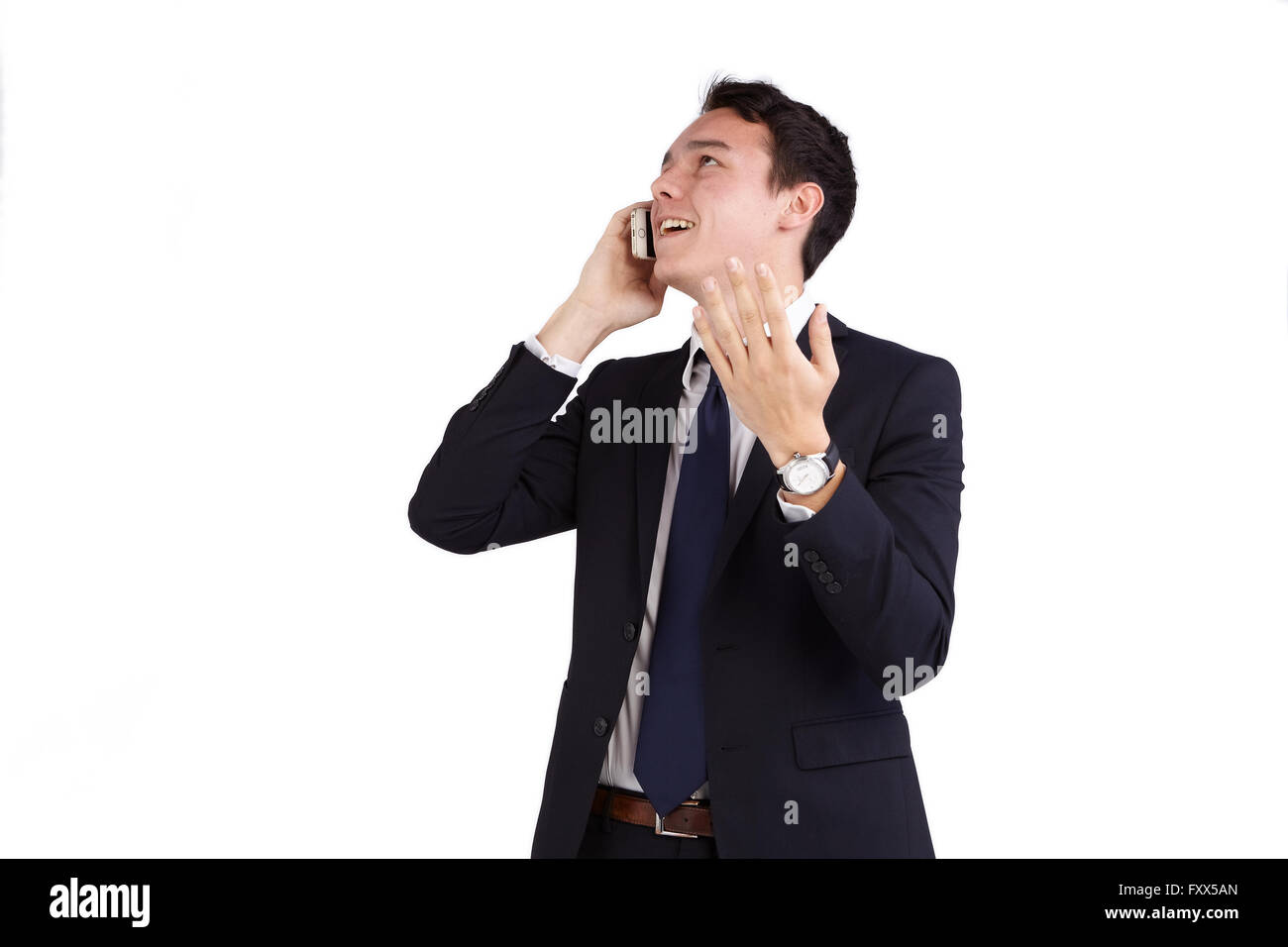 A young caucasian male businessman smiling with raised hand holding a mobile phone looking away from camera. Stock Photo