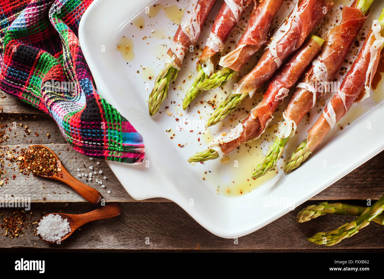 Fresh green asparagus wrapped in parma ham in pan, top view Stock Photo