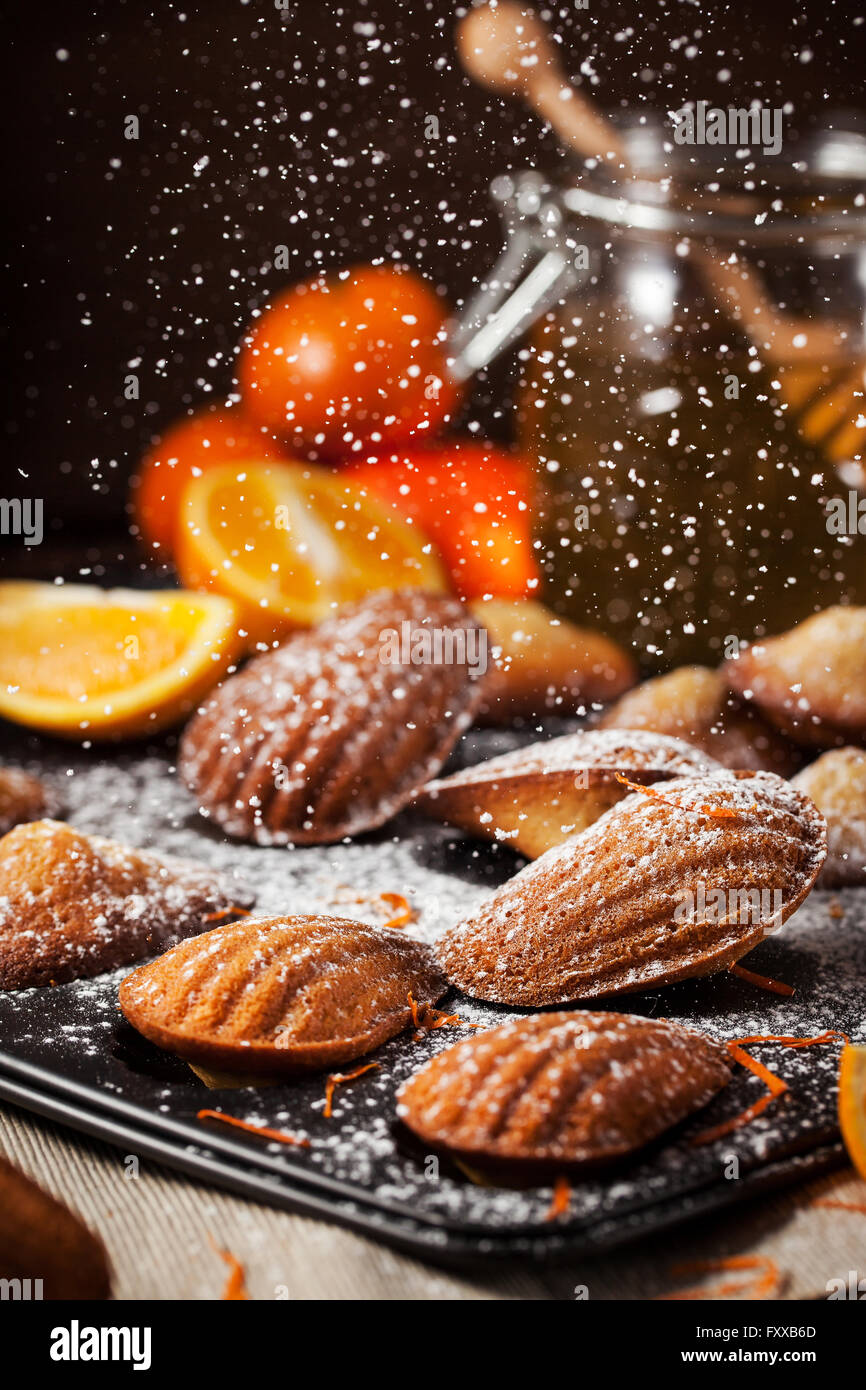 Homemade orange honey madeleines cookies and sugar powder motion Stock Photo