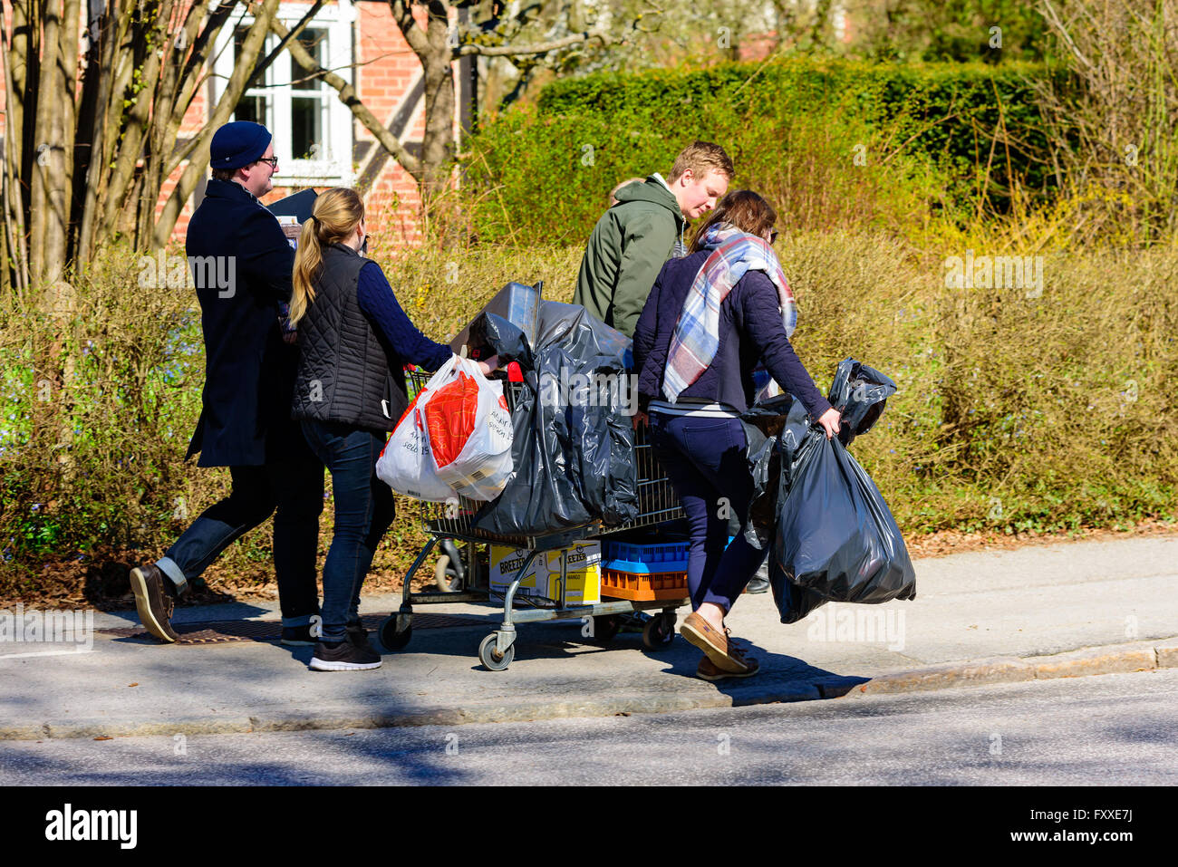 Lund, Sweden - April 11, 2016: Real life in the city. Some young adult persons help each other to move stuff with a shopping car Stock Photo