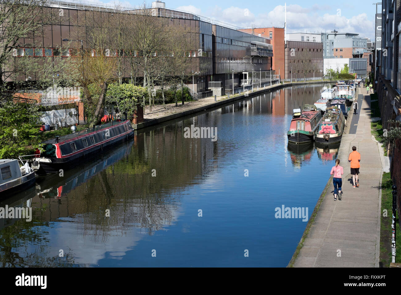 Runners pass narrow boats moored on the Regents Canal near King's Place, King's  Cross, London, England, UK Stock Photo
