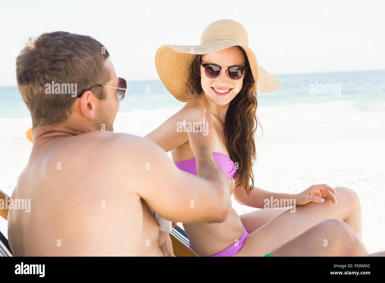 Boyfriends applying sun cream on girlfriend Stock Photo