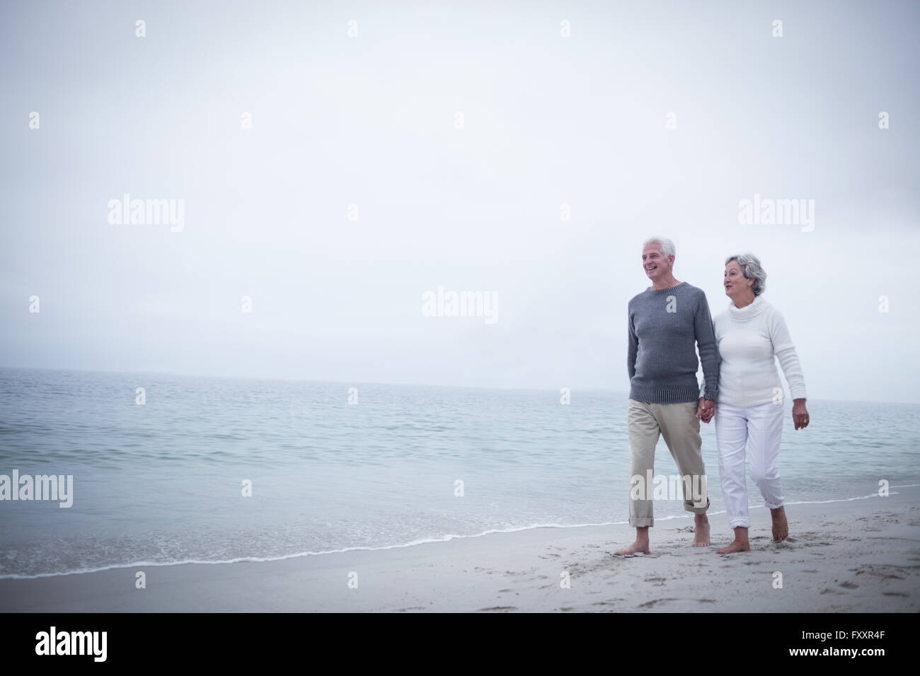 Senior couple holding hands and walking on the beach Stock Photo - Alamy