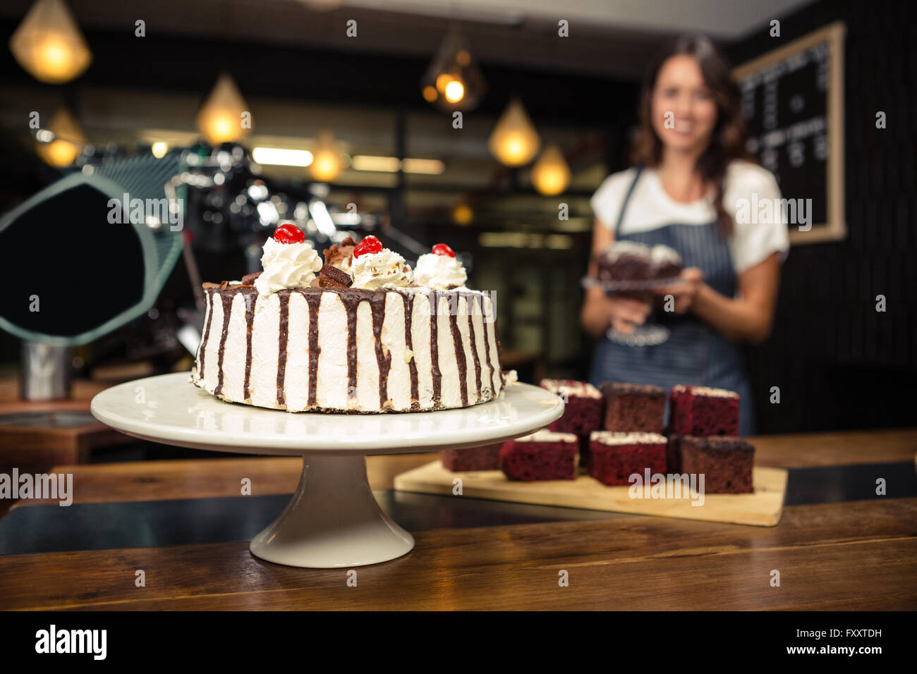 Smiling barista holding plate with cake Stock Photo
