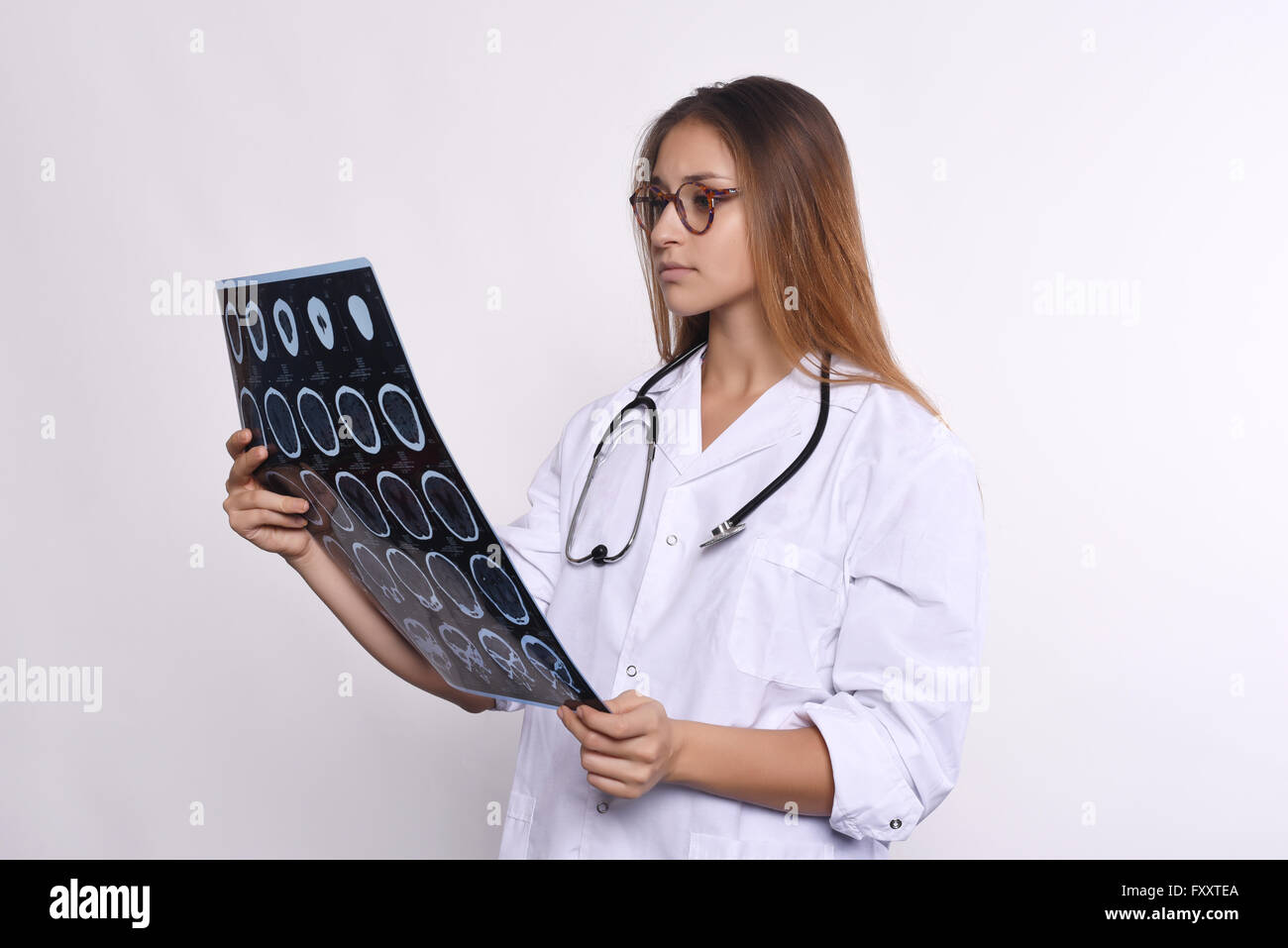 Portrait of young woman doctor with stethoscope and MRI scans. Isolated white background Stock Photo