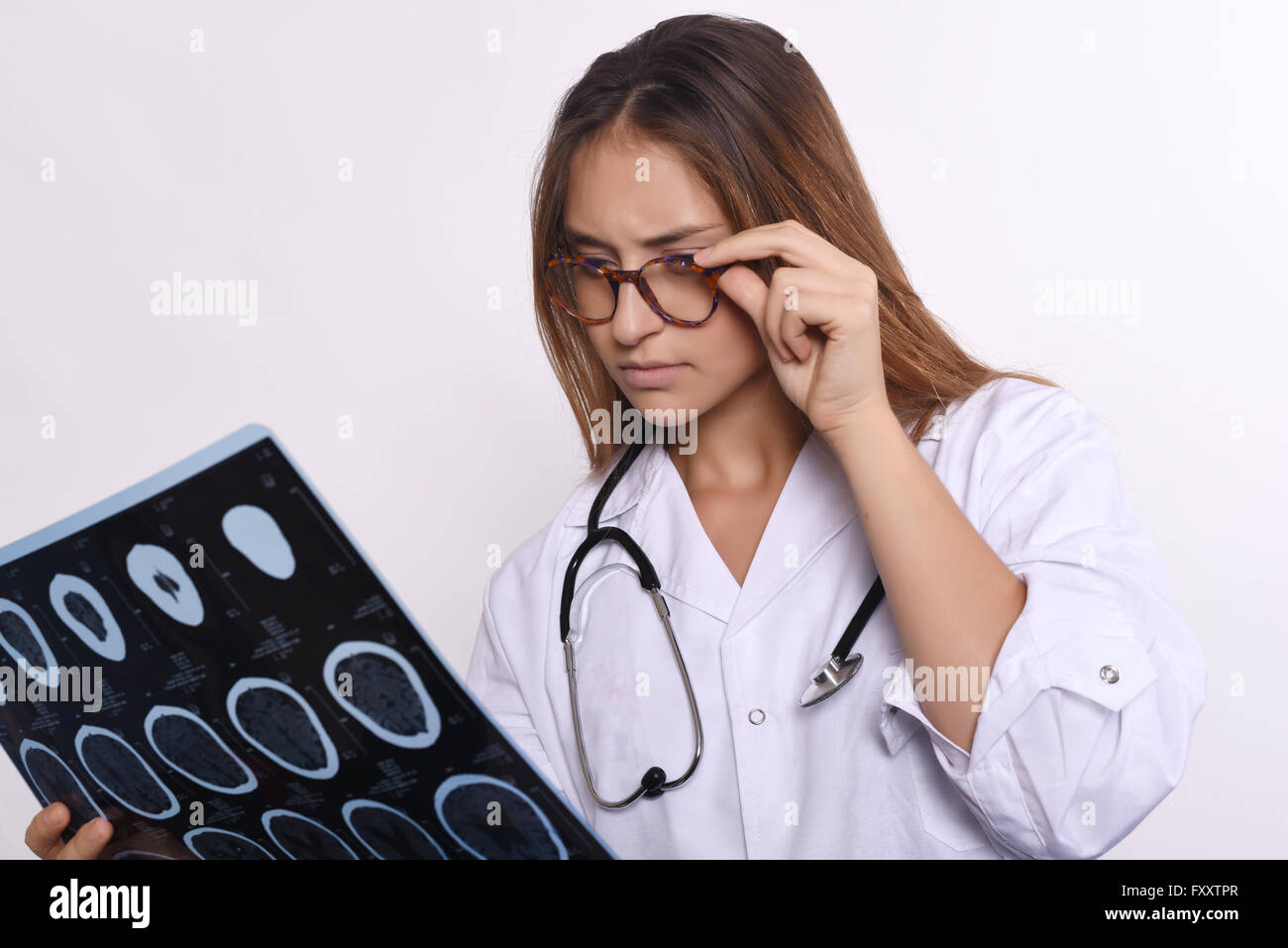 Portrait of young woman doctor with stethoscope and MRI scans. Isolated white background Stock Photo