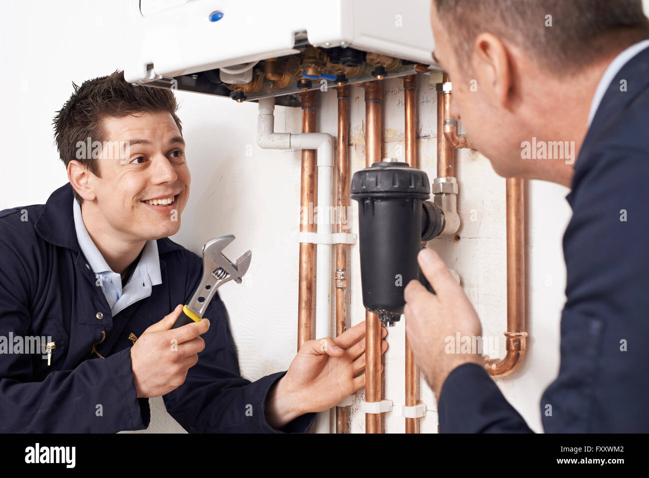 Trainee Plumber Working On Central Heating Boiler Stock Photo