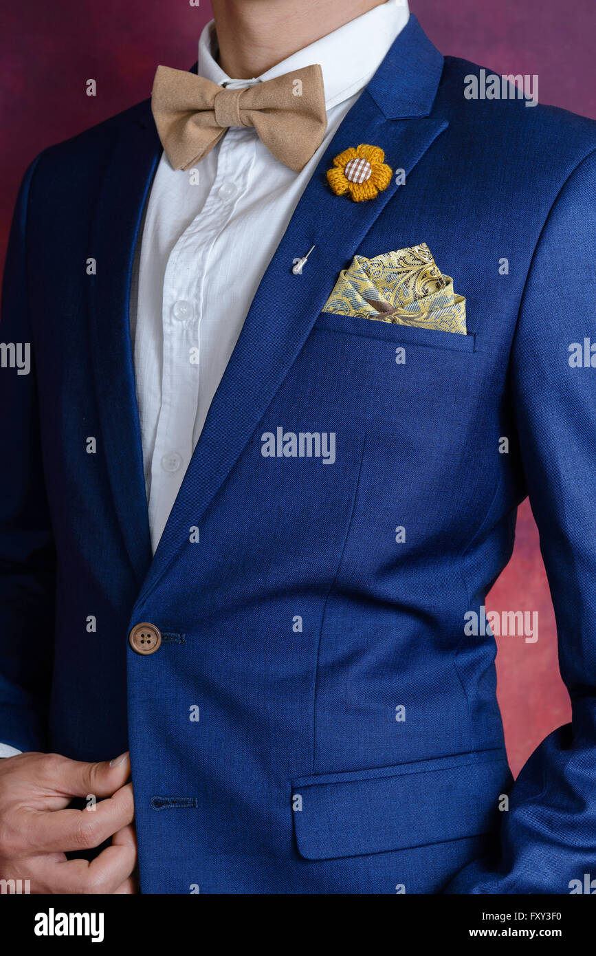 Man in blue suit with brown bow tie flower brooch and classic texture pocket square close up Stock Photo Alamy