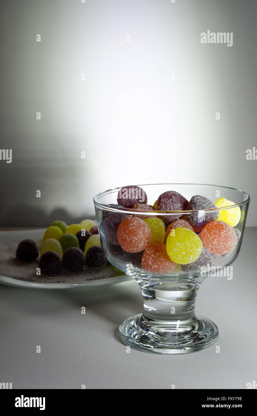 A Studio Photograph of American Hard Gum Sweets in a Clear Stemmed Bowl and on a White Serving Plate Stock Photo