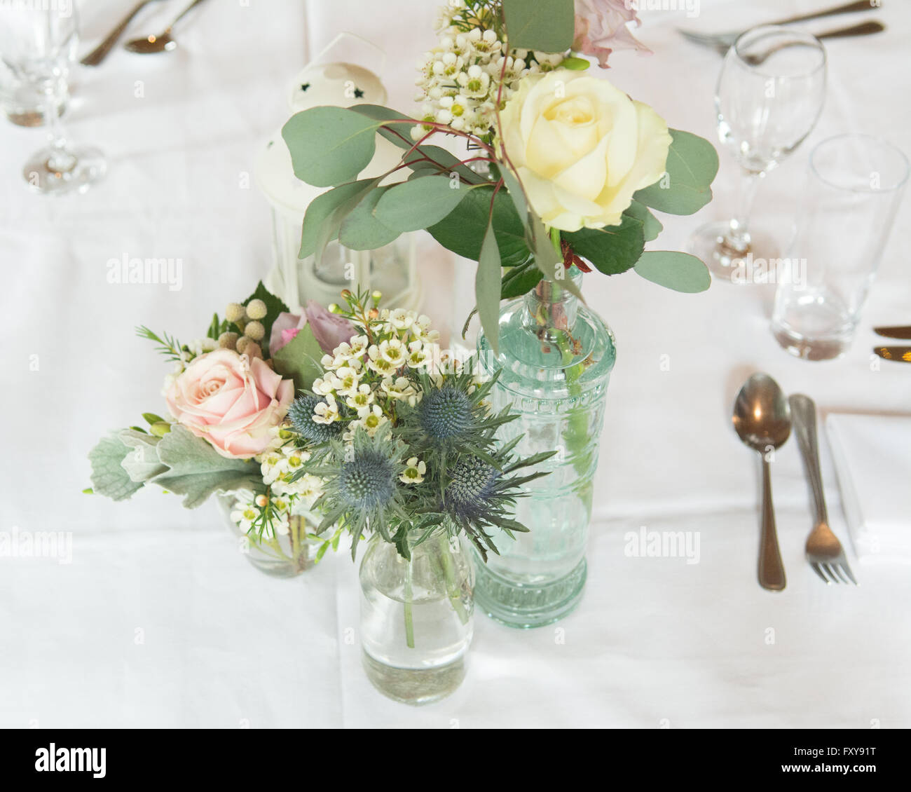 Table set for wedding or event with informal flower arrangements in vintage bottles Stock Photo