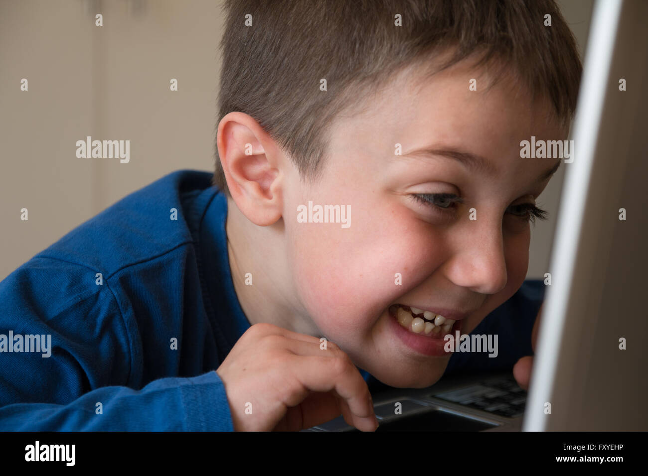 Joking Child in Front of Touch Screen Laptop, tongue stuck out Stock Photo