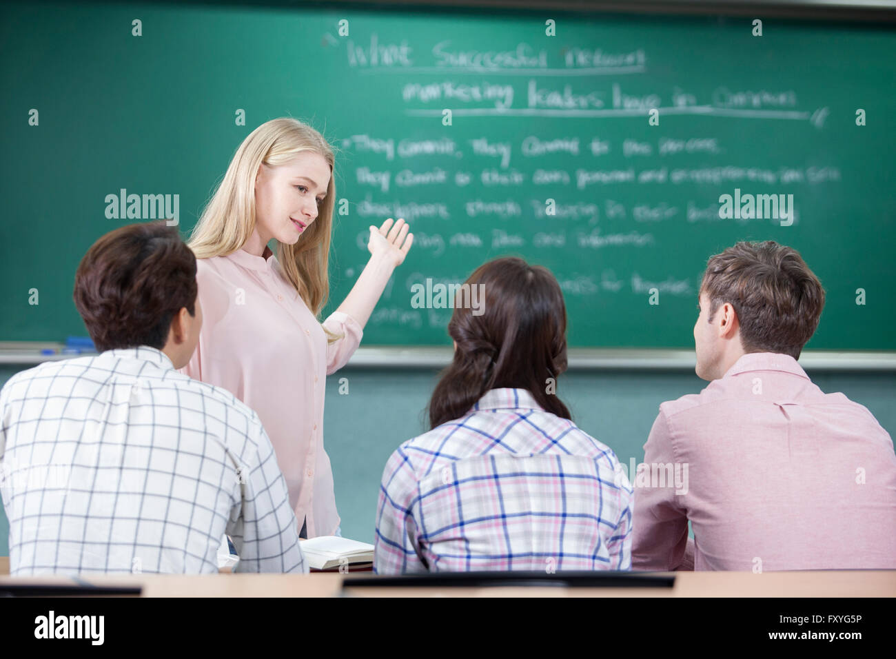 Foreign woman teaching a class and students looking at her representing global education Stock Photo