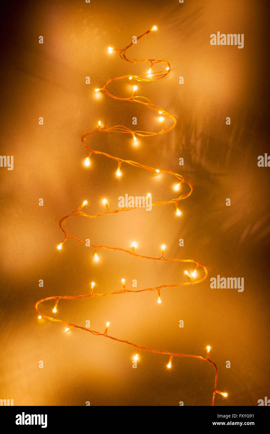 Christmas lights in Christmas tree shape in yellow light blurred Stock