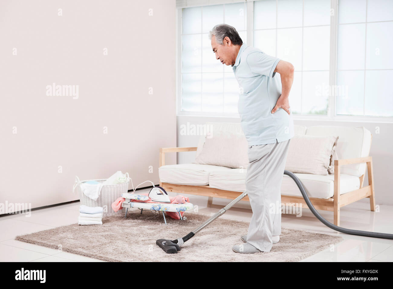 Senior man vacuuming and feeling pain on his back Stock Photo Alamy