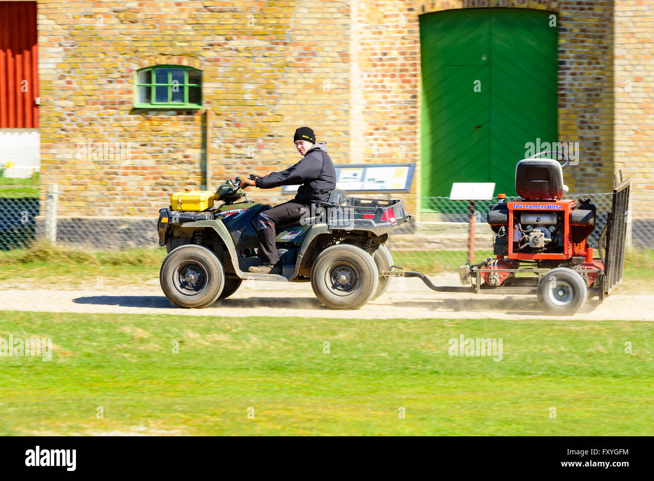 Falsterbo, Sweden - April 11, 2016: Young adult male driving a Polaris Sportsman 550 awd with a trailer on a dirt road. Stock Photo