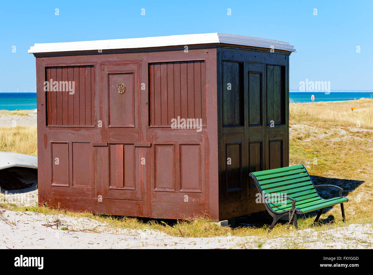 Falsterbo, Sweden - April 11, 2016: Brown rectangular wooden beach hut or bathing cabin along the sandy shoreline. Dry grass and Stock Photo