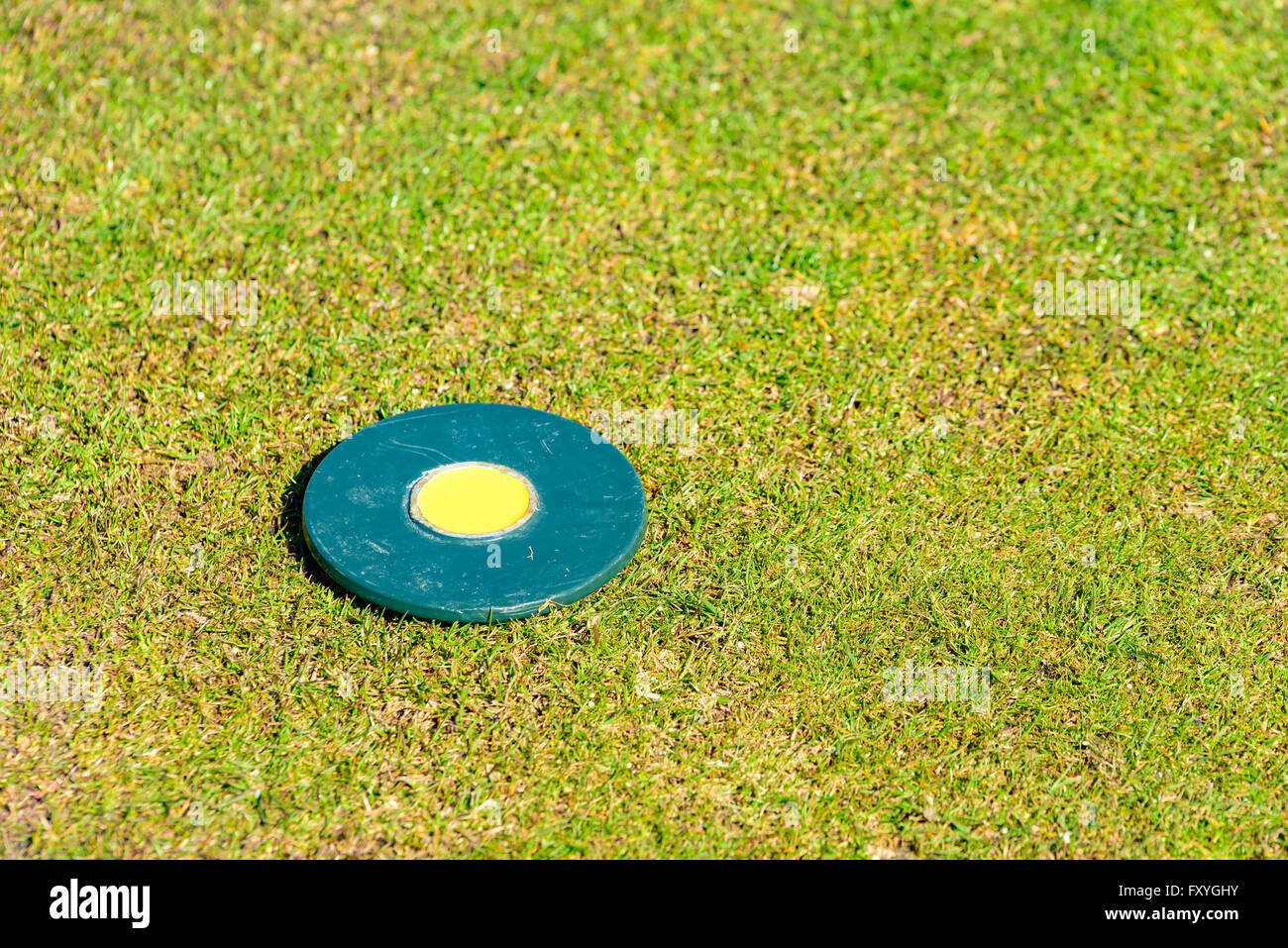 Circular marker lying on tee on a golf course. Nicely cut grass surround it. Copy space. Stock Photo
