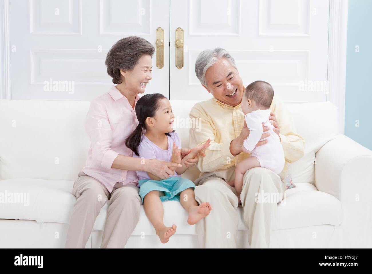 Grandparents being happy with their grandchildren all seated on a couch and smiling Stock Photo