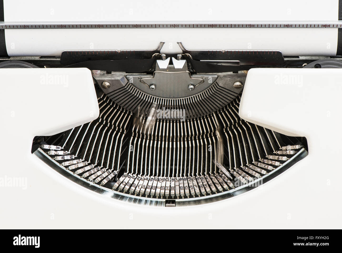Detail view of an old fashioned typewriter from the 1970s with blank paper and moving hammer heads Stock Photo