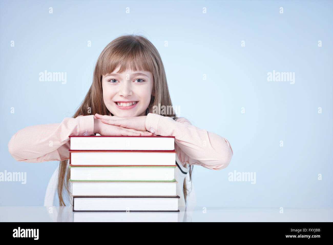 Girl resting her head and arms on a pile of books Stock Photo - Alamy