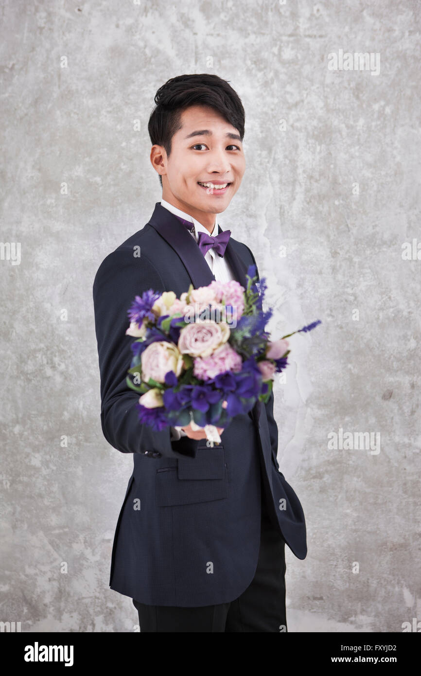 Bridegroom holding a bouquet forward with a smile Stock Photo
