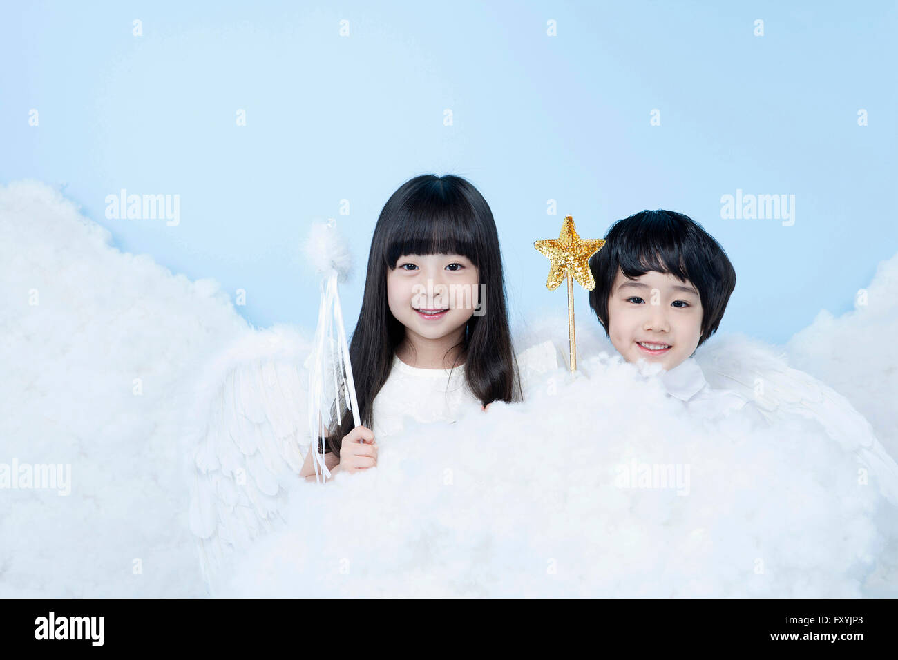 Boy and a girl with magic sticks in clouds in the background representing heaven Stock Photo